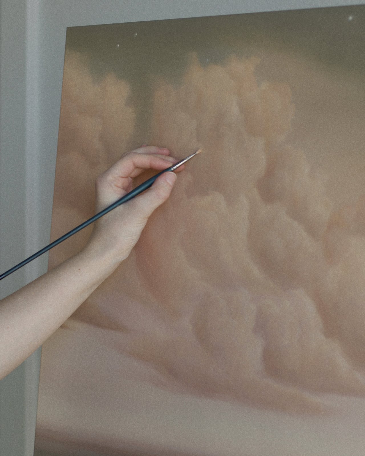 Savannah Morgan's hand adding stars to a painting with a fine brush